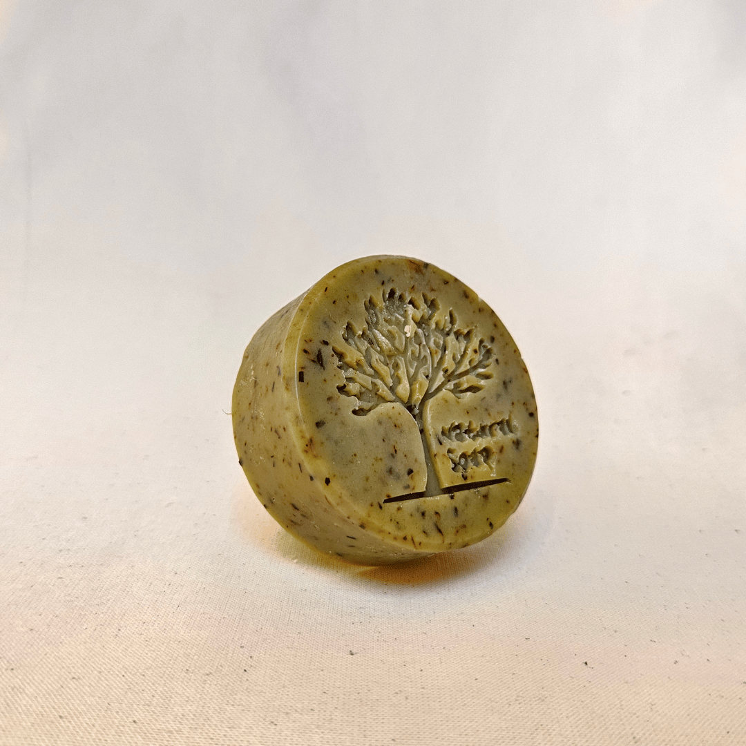 Rund, mat grøn sæbe med et aftryk af et træ. 